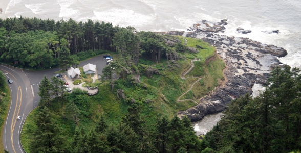 [A small jut of land with a zig-zag path to the bottom of the hill where the ocean water goes into a narrow inlet. It's low tide so dark-colored land at the bottom of the green hillside is visible.]